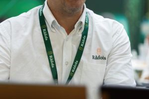Persona con camisa blanca y acreditación de Ràfols en un evento profesional.