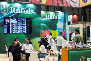 Stand de Ràfols en una feria comercial con varias personas reunidas en mesas para mantener reuniones.