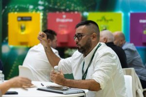 Persona sentada en una mesa durante una reunión en el stand de Ràfols, gesticulando mientras conversa.