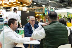Varias personas reunidas alrededor de una mesa manteniendo una conversación en una feria comercial.