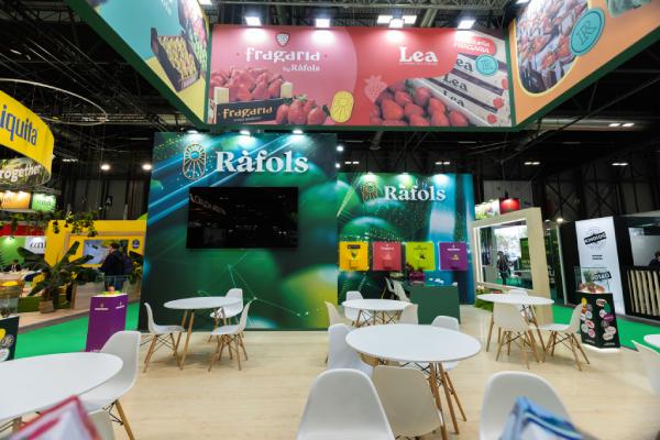 Estand de Ràfols en una feria, con mesas y sillas para reuniones, un monitor en la pared y paneles superiores con las marcas Fragaria y Lea.