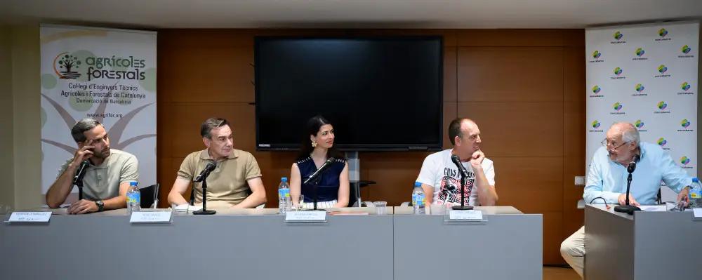 Participantes de una mesa redonda en una jornada de Mercabarna sentados ante micrófonos, con paneles del Col·legi d’Enginyers Tècnics Agrícoles i Forestals de Catalunya al fondo.