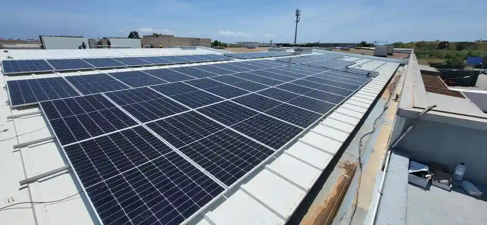 Instalación de placas solares fotovoltaicas sobre la cubierta de un edificio industrial en un día soleado.