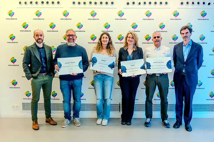 Seis personas posan frente a un panel con el logotipo de Mercabarna durante una entrega de reconocimientos, con varias de ellas sosteniendo diplomas.